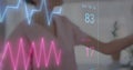Image of colourful cardiographs over diverse female nurse and patient in hospital bed Royalty Free Stock Photo