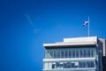 The Quebec Fleurdelise flag flies above a modern glass office building in Montreal, Canada. A clear sky and clean lines link Royalty Free Stock Photo