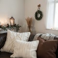 Composition of candles on white table against the background of sofa with plaids and pillows Cozy home concept