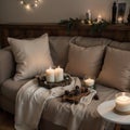 Composition of candles on white table against the background of sofa with plaids and pillows Cozy home concept
