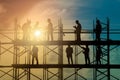 Image Construction workers on scaffold working in intense sunlight, shadowed silhouette