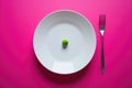 An image that conveys minimalism and restraint, showcasing a lone green pea placed artfully on a white plate against a