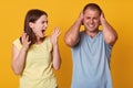 Image of couple quarrel, irritated angry screaming woman opening mouth widely, raising her arms, looking at husband. Annoyed young Royalty Free Stock Photo