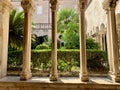 an image of a courtyard with columns and bushes in the foreground