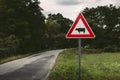 Image - Cow traffic european sign red triangle with curved road, green meadow and field on background on sunset. Beware of the Royalty Free Stock Photo