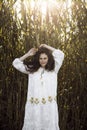 Image of a curly girl with speckle dressed in a white dress, field background.