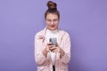 Image of cute charismatic attractive young female holding smartphone, using device, looking at its screen attentively, having