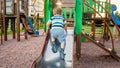 Photo of cute 3 years old toddler boy climbing and riding on big slide on children playground at park Royalty Free Stock Photo