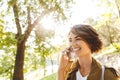 Cute young amazing woman walking outdoors in park in beautiful spring day talking by mobile phone Royalty Free Stock Photo