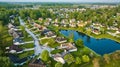 Dark blue pond with cul-de-sac and housing neighborhood suburban homes in summer aerial Royalty Free Stock Photo