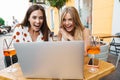 Image of delighted women expressing surprise while using laptop