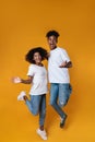 Image of delighted african american couple laughing while jumping