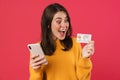 Image of delighted caucasian girl posing with cellphone and credit card