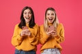 Image of delighted nice women smiling while using smartphones