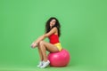 Image of delighted woman 20s wearing summer clothes holding dumbbells while sitting on fitness ball during aerobics Royalty Free Stock Photo