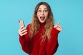 Image of delighted woman using cellphone and pointing finger upward