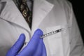 Close-up image of vaccine syringes with a gloved doctor in the soft background.