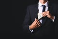 Businessman putting bribe in pocket against dark background. Concept of corruption Royalty Free Stock Photo