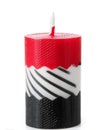A burning decorative candle in red, white, and black tones, isolated on a white background. Royalty Free Stock Photo