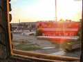 Image depicts a dynamic, time-lapse view of an industrial setting through barred windows The scene shows stacks of