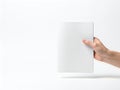 A hand holding a white rectangular object in front of a plain background Royalty Free Stock Photo