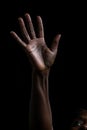 a african american woman reaching up with her hand for help. isolated black background. reaching out to help. Helping hand.