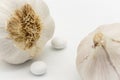 Close-up of a pair of dried Garlic bulbs shown together with a mock-up of Garlic supplement tablets.