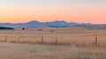 A serene sunset over a vast, dry field with a fence in the foreground. Royalty Free Stock Photo