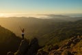 Woman with arms raised stands on mountaintop at sunrise Royalty Free Stock Photo