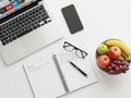 Workstation setup with notebook and fruit bowl isolated on white background Royalty Free Stock Photo