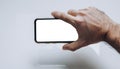 Hand holding smartphone with blank screen against plain neutral background showcasing modern device usage in everyday life Royalty Free Stock Photo