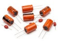 Assorted orange cylindrical electronic capacitors with leads on a white background Royalty Free Stock Photo