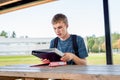 Happy teenager studying outdoors at a picnic table. Royalty Free Stock Photo