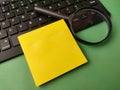 The image displays a yellow sticky note placed on a black computer keyboard alongside a magnifying glass Royalty Free Stock Photo