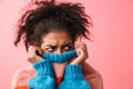 Displeased beautiful young african woman posing over pink wall background covering face with sweater