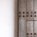 Image divided in half of an old wooden door with large nails and white wall background. Square format 1x1