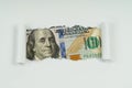 An image of a 100 dollar bill is visible in the torn hole of a sheet of paper Royalty Free Stock Photo