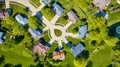 Downward rooftop view of eight suburban neighborhood homes of varying colors near pond aerial Royalty Free Stock Photo