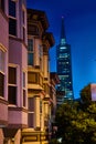 Eerily lit apartment buildings at night with Transamerica Pyramid looming out of fog