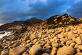 Nature Seascape with Eggshaped Rocks on A Wild Beach and Rocky Mountains at Dramatic Sunrise