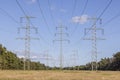 Image of an electricity pylon from the ground perspective in front of a blue sky with white clouds Royalty Free Stock Photo