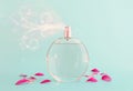 Image of elegant perfume bottle spraying over blue pastel background