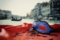 Image of elegant venetian mask on red silk fabric in front of blurry Venice background. Royalty Free Stock Photo