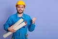 Image of energetic bearded cheerful handsome worker standing isolated over blue background in studio, keeping fist, holding