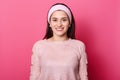 Image of european lovely woman with dark hair, wears rose sweater. Lady being in good mood while posing alone in studio. Young