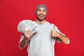 Image of european man 30s wearing hat holding money fan, isolated over red background Royalty Free Stock Photo