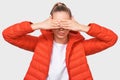 Image of European young woman in casual red jacket, covering her eyes with both hands, waiting for a surprise for her birthday. Royalty Free Stock Photo