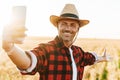 Image of excited adult man taking selfie on cellphone at cereal field