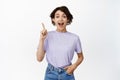 Image of excited brunette female model pointing finger up, look in awe, showing advertisement sale upwards, got an idea