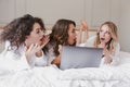 Image of excited surprised women 20s wearing white housecoat lying in luxury bedroom at home, and using silver laptop during hen